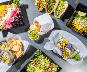 Overhead view of many menu items, including tacos, burritos, and salads from the Avocado Pit. 